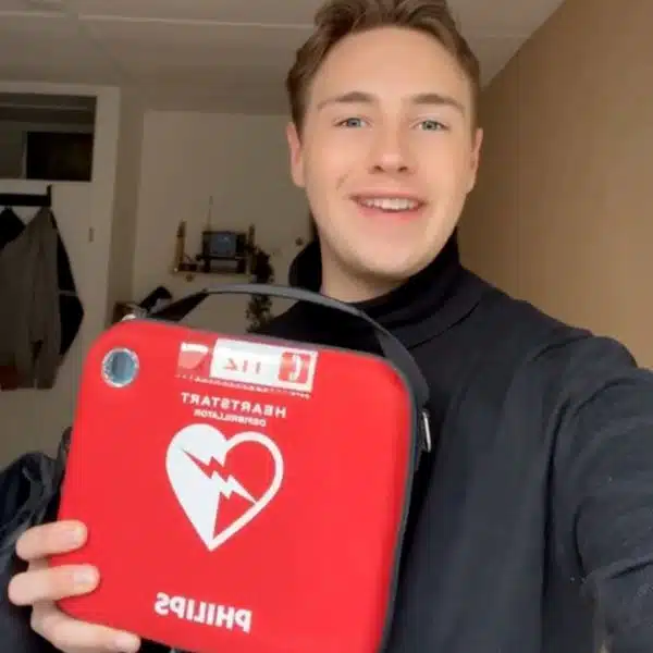 Mann hält roten Philips AED-Koffer und lächelt